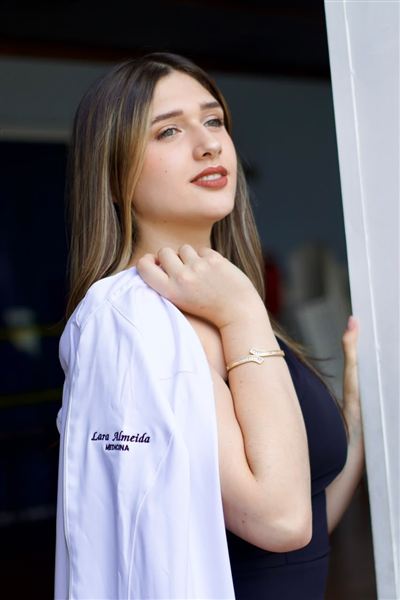 Estudante de medicina com o jaleco no ombro em ensaio de meio curso