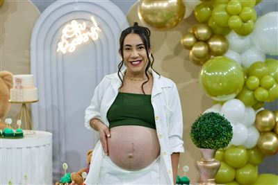 Gestante sorrindo em frente à decoração do chá de bebê