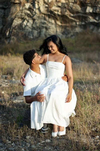 Casal sorrindo em ensaio ao ar livre ao pôr do sol