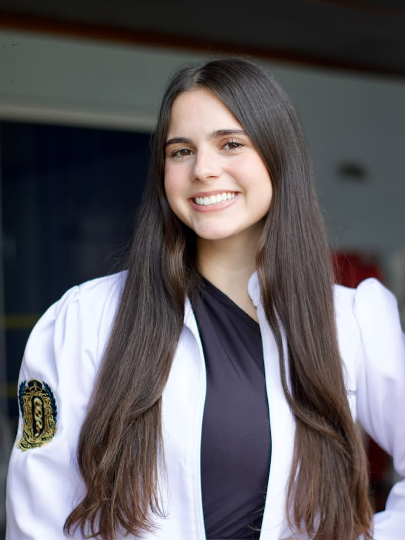 Estudante de medicina de cabelo longo sorrindo com a mão na cintura
