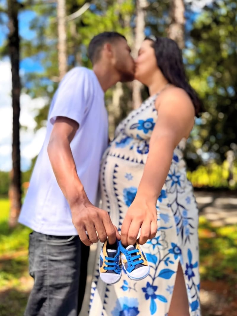 Casal se beijando segurando um par de tênis de bebê