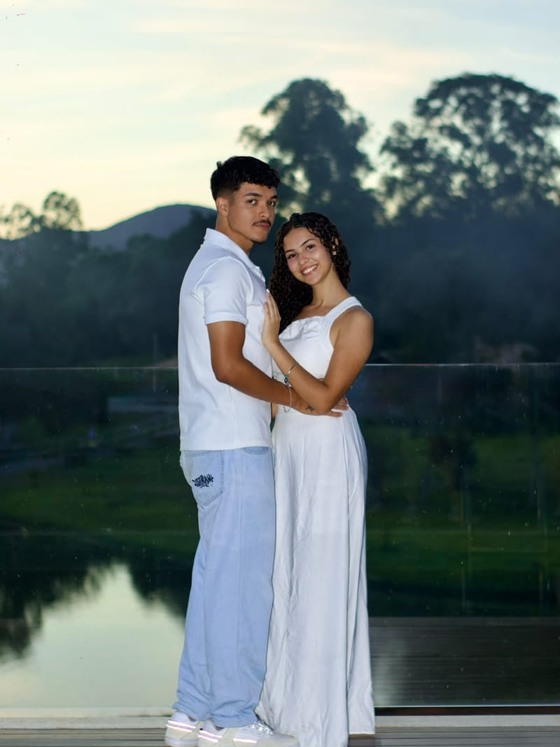 Casal de branco abraçado no deck à beira do lago, ao entardecer